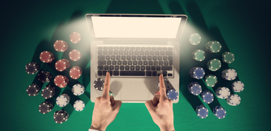 gestapelte Pokerchips links und rechts von einem Laptop